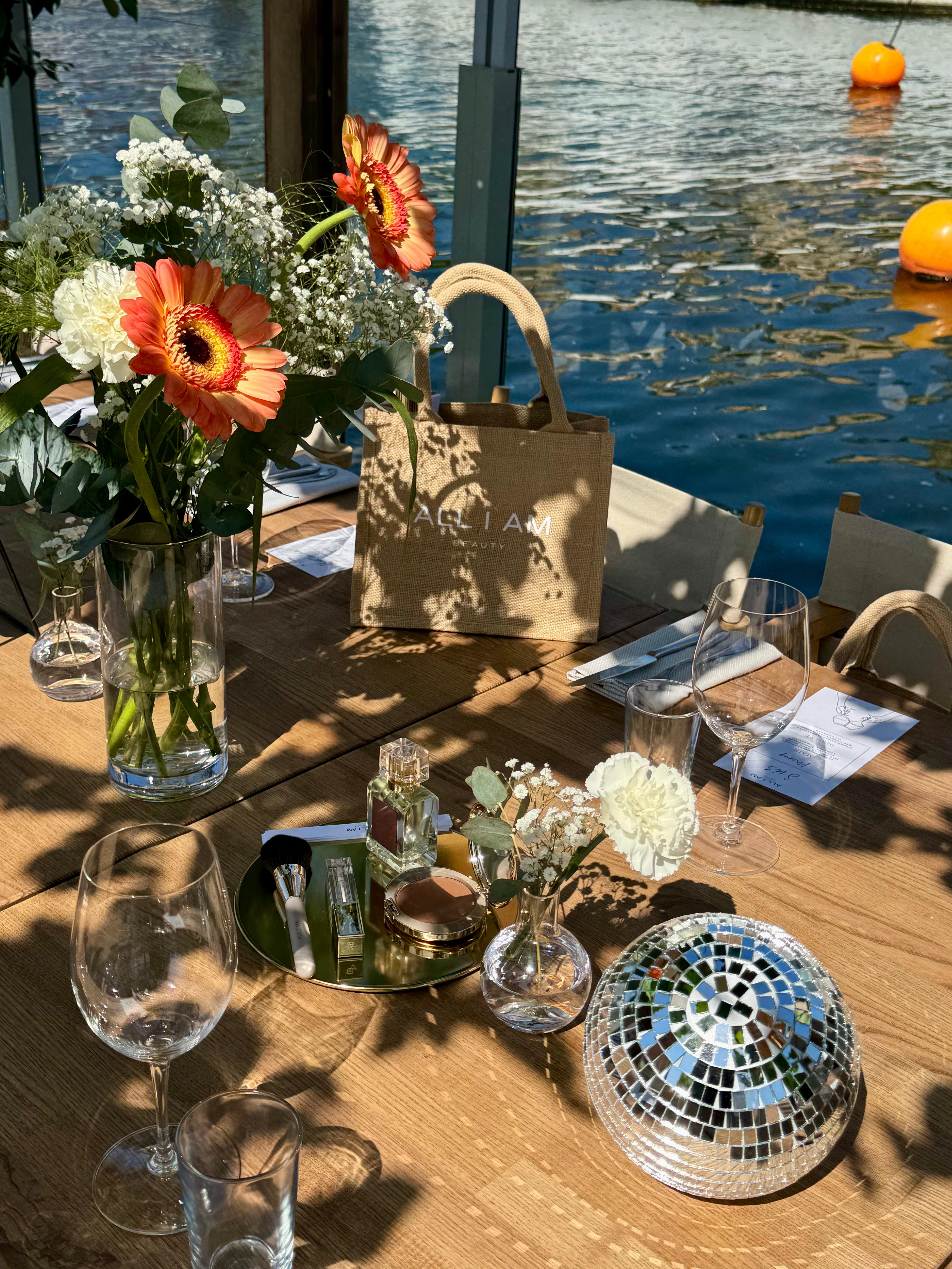 All I AM Beauty tote bag styled on an outdoor event table with flowers and a disco ball